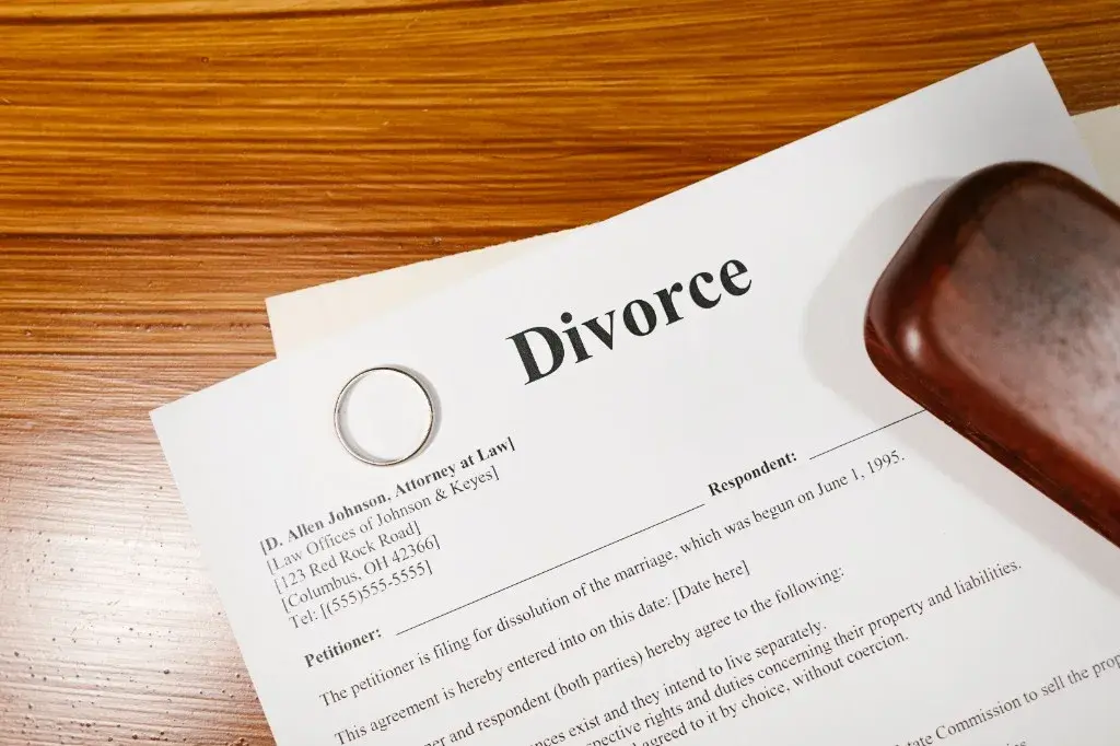 Divorce paperwork with a wedding ring and gavel on a wooden desk